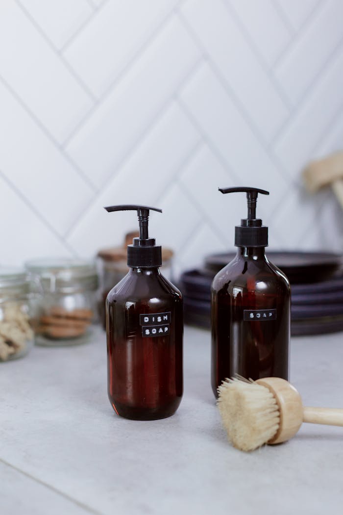Minimalist kitchen setting featuring dish soap dispensers and cleaning brush on countertop.